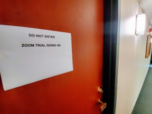 office door with sign reading "DO NOT ENTER ZOOM TRIAL GOING ON"